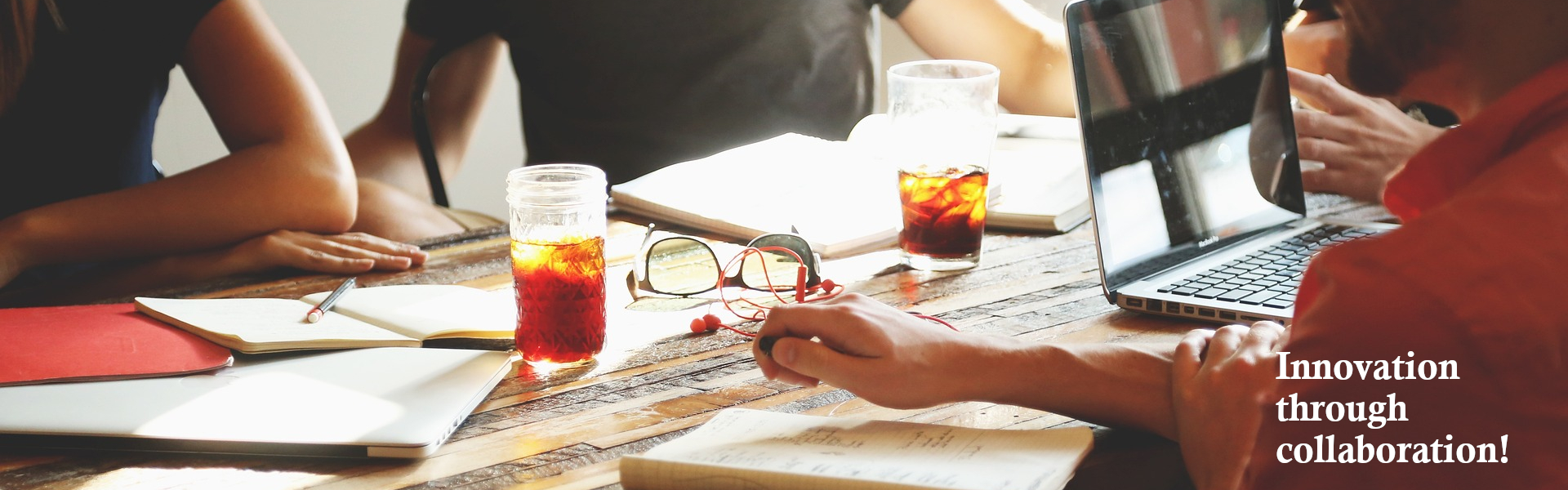 Picture of meeting round a table with a caption of: Innovation through collaboration